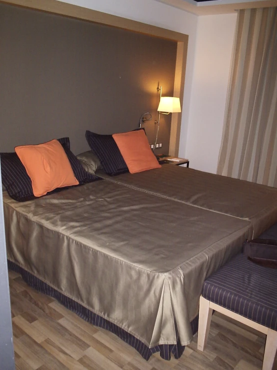 a bed in a bedroom with wooden floors and striped curtain