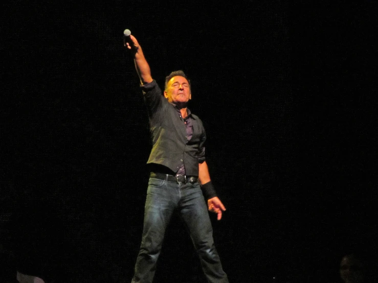 a male in a black shirt is on stage holding his arms up