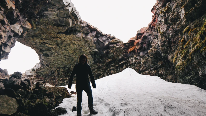 a woman stands in the snow underneath some rock arches