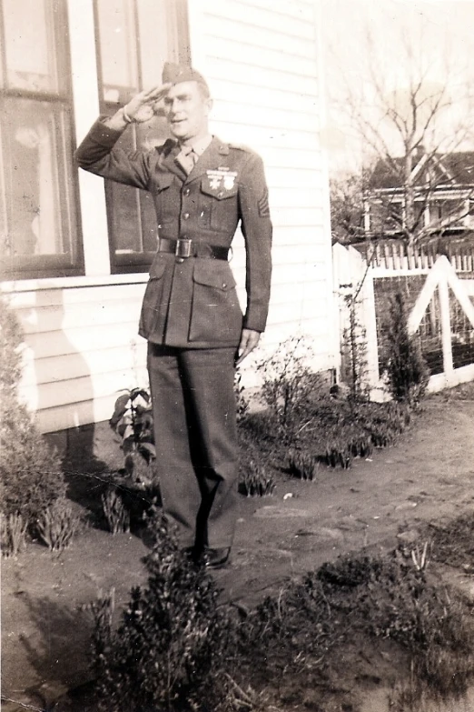 a man in a military uniform stands outside of a house