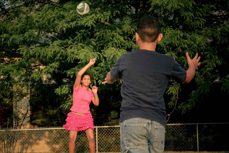 two children are playing with a soccer ball in their backyard