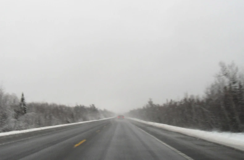 a snowy road in the country with a few trees