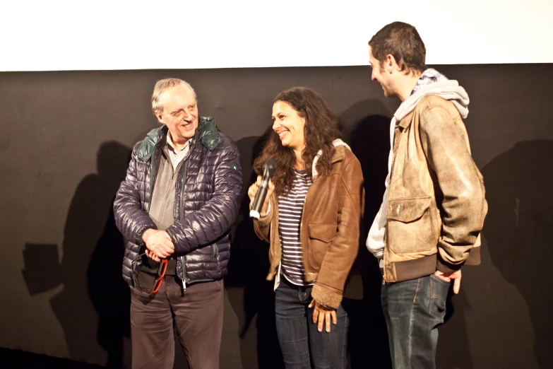 four people standing together in front of a wall