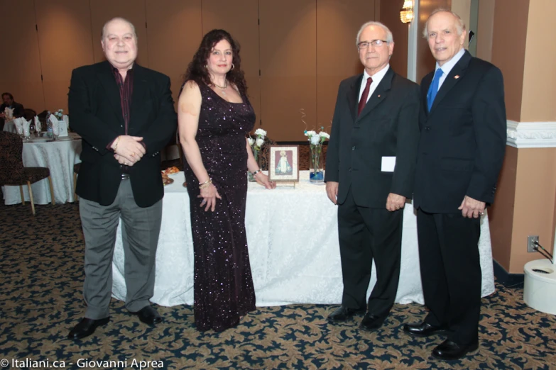 four people in evening wear standing near a table