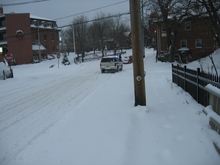 car parked on snow covered side walk with street sign in background