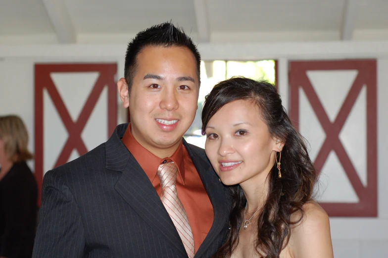 man and woman pose together in front of barn doors