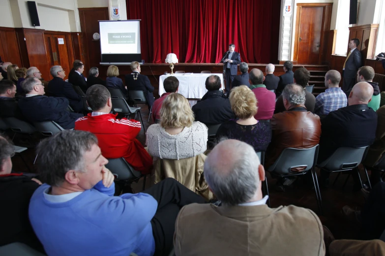 a group of people are in a meeting, many sitting down