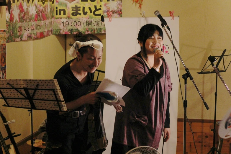 two men who are standing near microphones and in front of a speaker