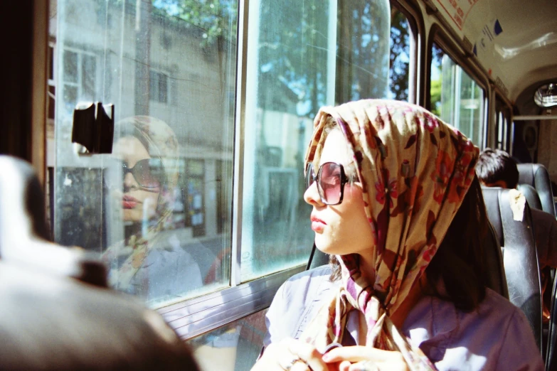 a woman wearing head scarves looking out the window