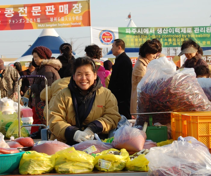 woman smiles near an outdoor market table with various produce