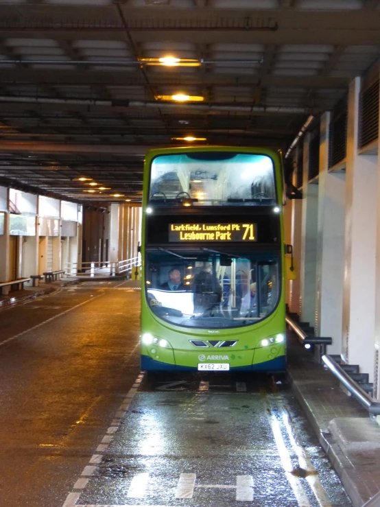 a green and blue bus is by itself under the roof