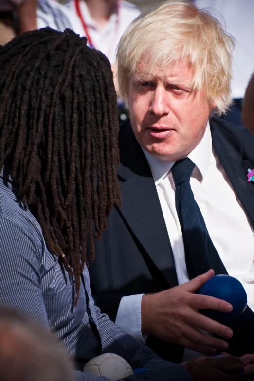 a woman in a suit talking to a man with dreadlocks