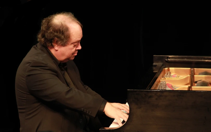a man in a black suit is playing piano