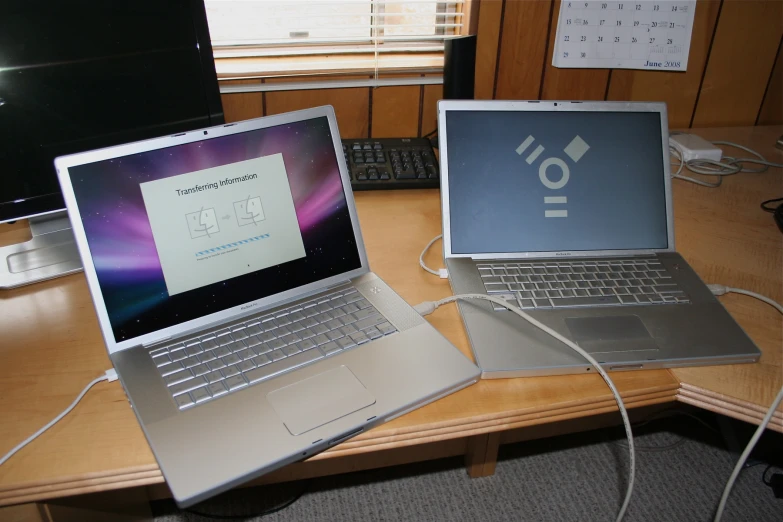 two computers that are turned on, one is connected to a phone