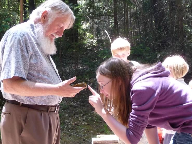 a man with white hair and beard standing next to a woman and giving food to them