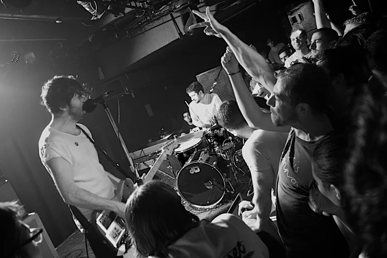 people standing on stage while one person holds his hands up in the air