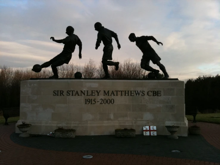 statue of four men in front of a statue of two boys playing