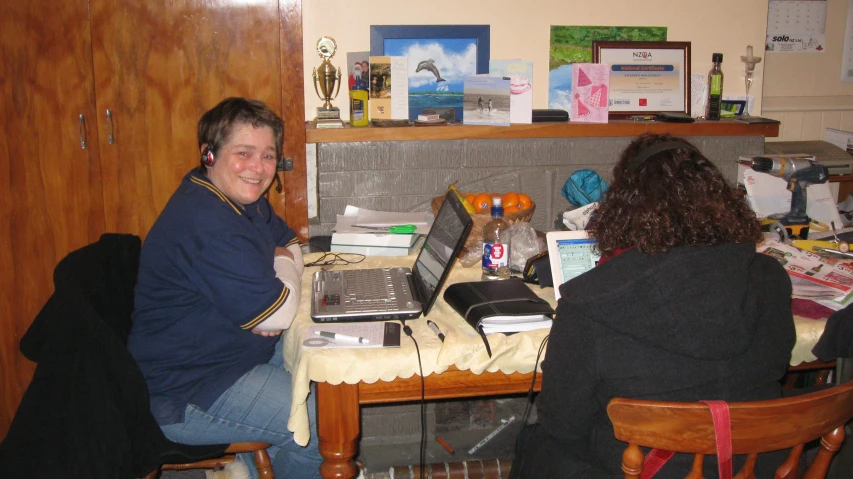 a man sitting at a table in front of a woman using a laptop computer