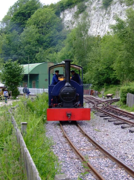 the train is on a railroad track in the woods