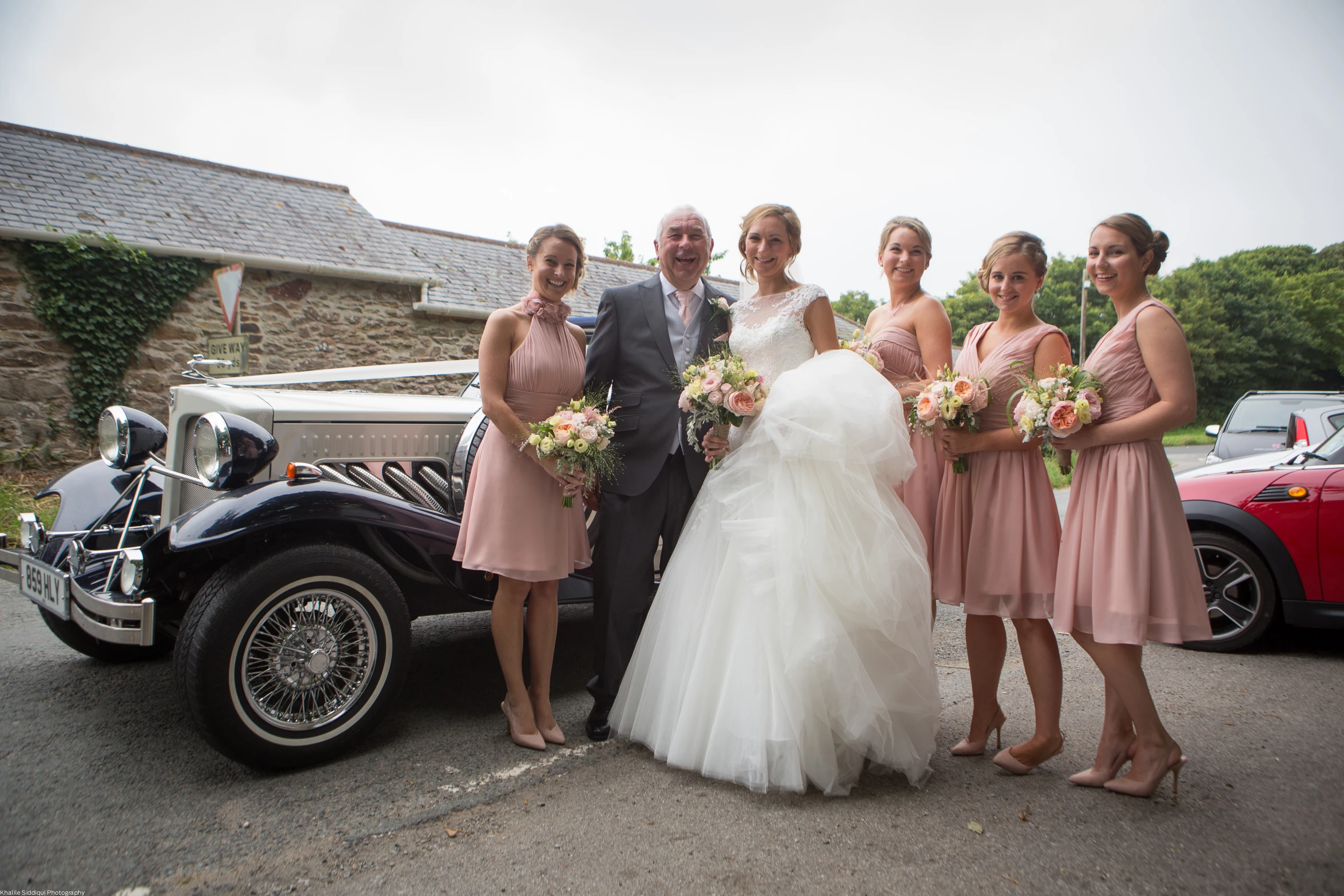 a bride and groom standing in front of a vintage car