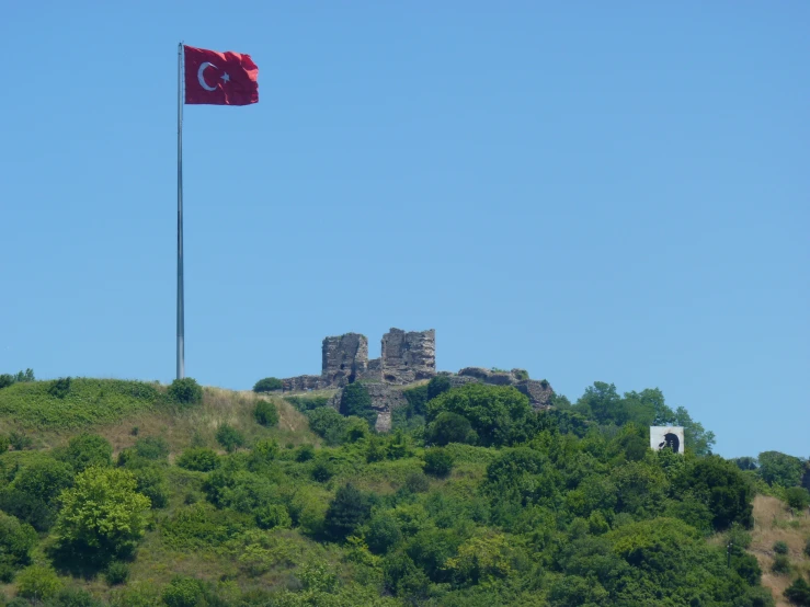 a red flag flies over the top of a hill