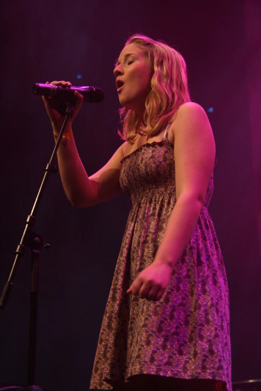a woman singing into a microphone in a concert