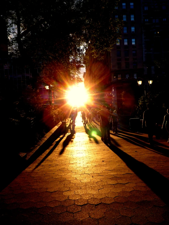 people walk along an empty street at sunset