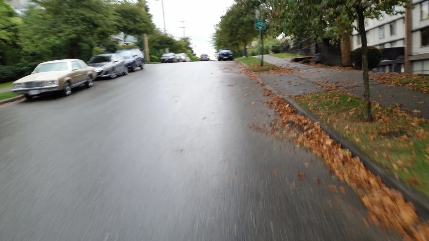 cars are parked on a wet street near apartment buildings