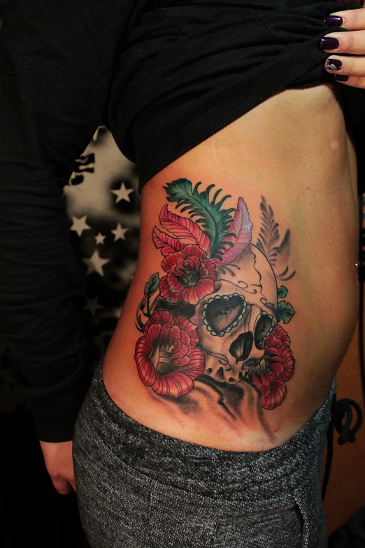 a girl's stomach showing a skull and flowers tattoo