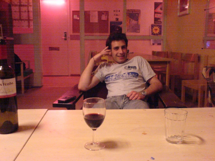 a man sitting at a table holding a glass of wine