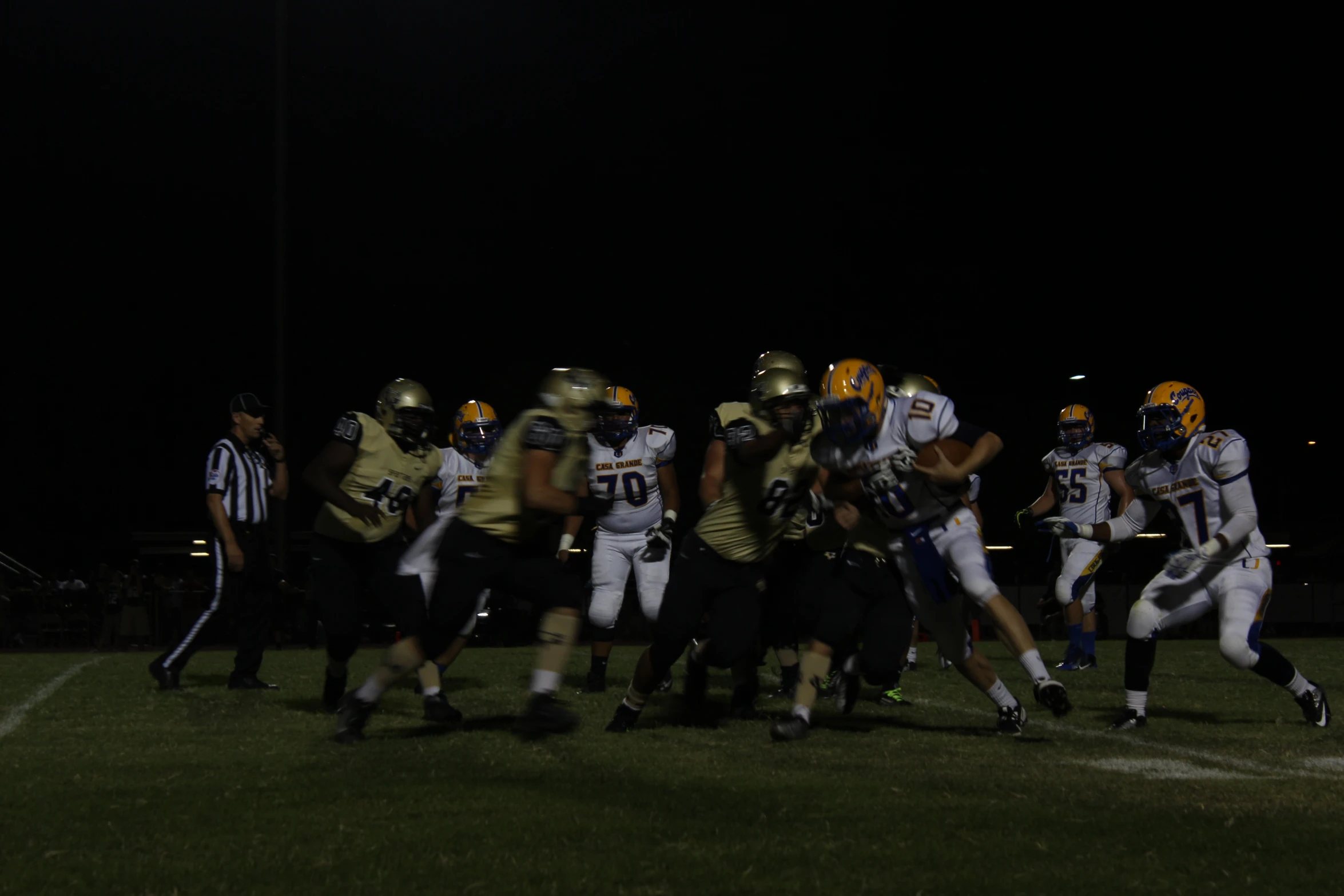 football players from opposing teams playing on a field at night