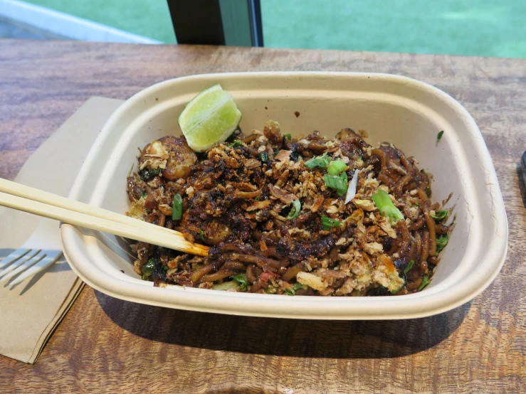 food in a dish with chop sticks sitting on top