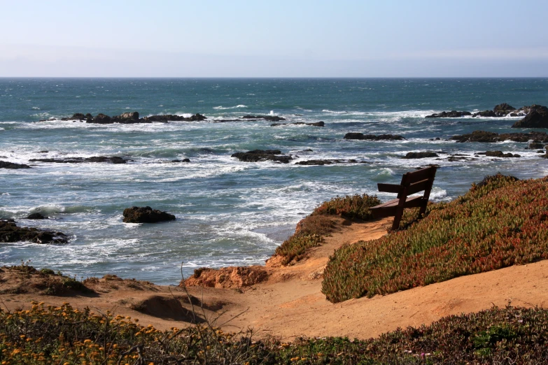 a bench on top of a cliff by the ocean