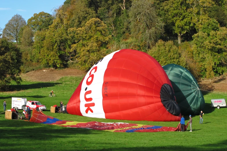 large kites lay on the ground with people standing around them