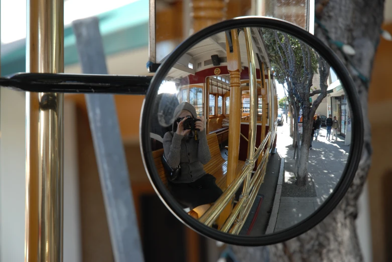 a mirror is shown showing a woman sitting in the train car