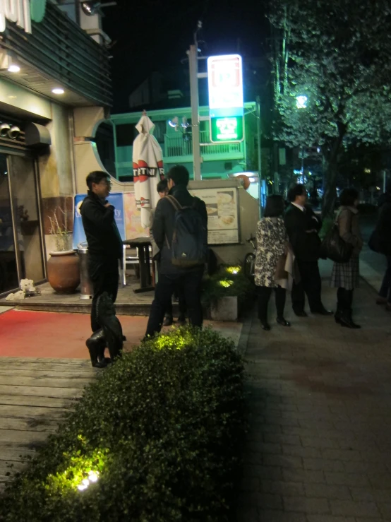 people standing on a sidewalk at night