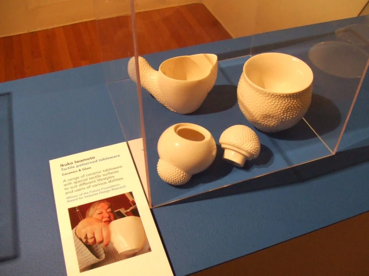 some white ceramic vases on display on blue table