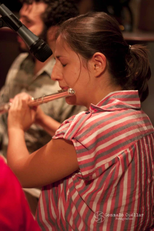 girl wearing red  shirt playing flute during concert