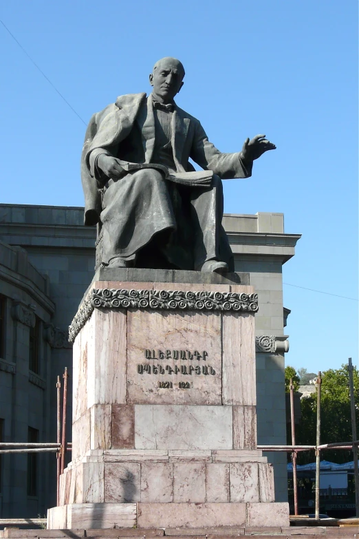 a large statue of a man holding a book in front of a building