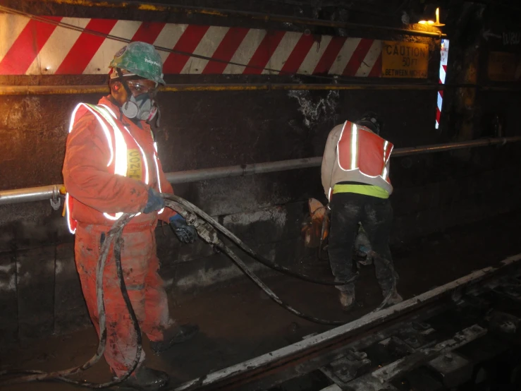 a man in an orange safety suit and white helmet working on train tracks