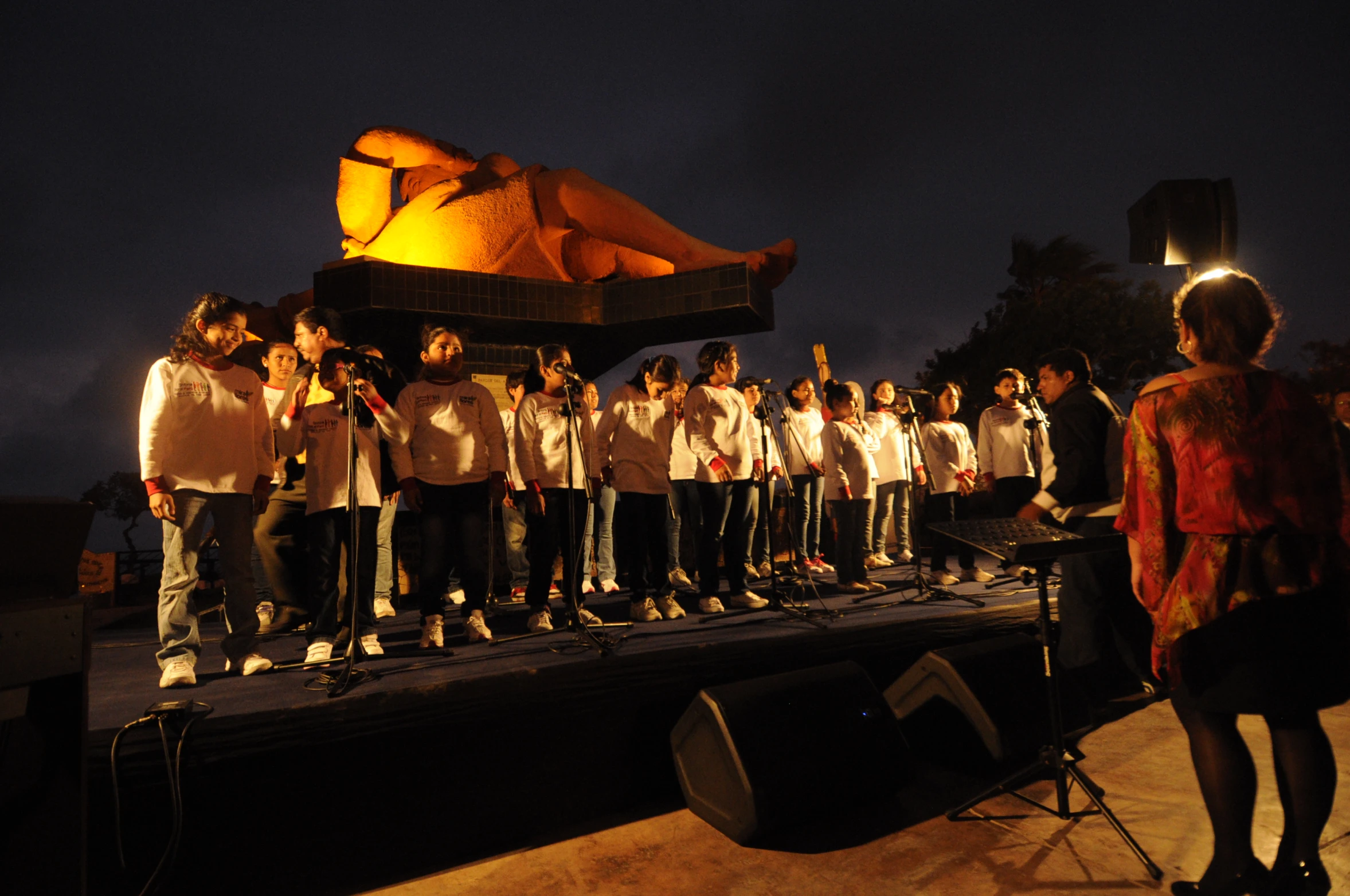 choir members performing on stage in front of an outdoor tent