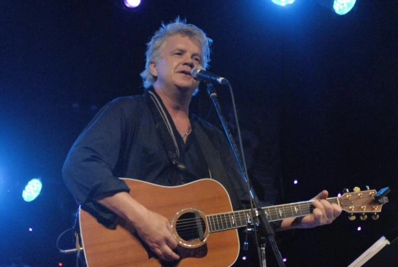 a man playing a guitar at the microphone