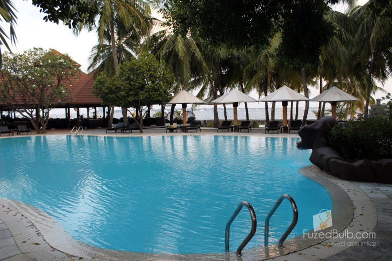 an empty pool with lounge chairs and umbrellas