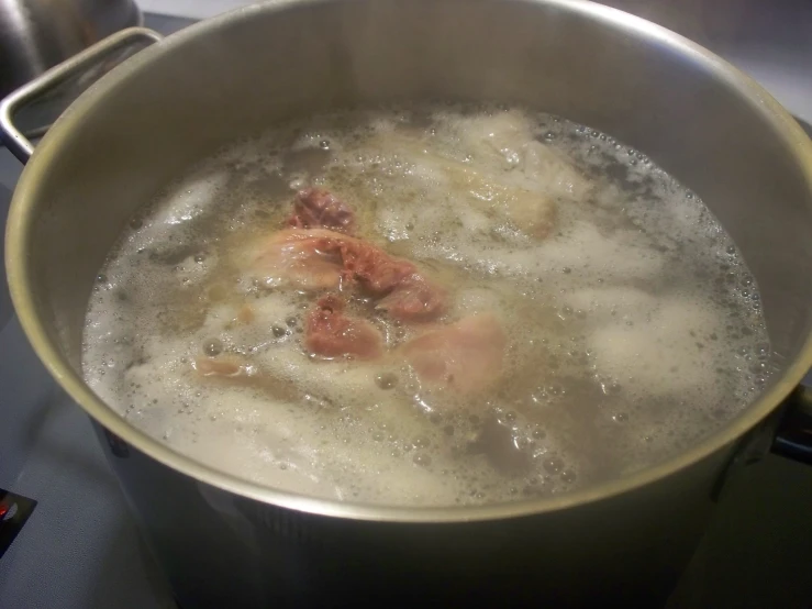 a pot full of boiling and meat with some sort of substance inside