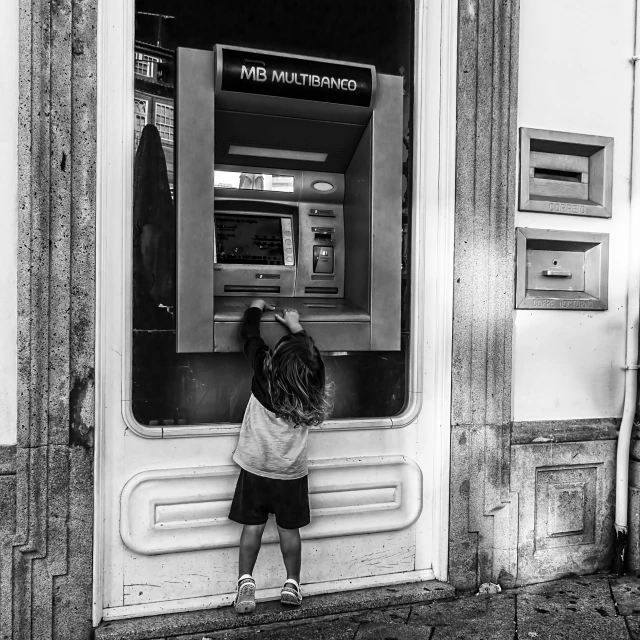 a person standing by a atm machine on the street