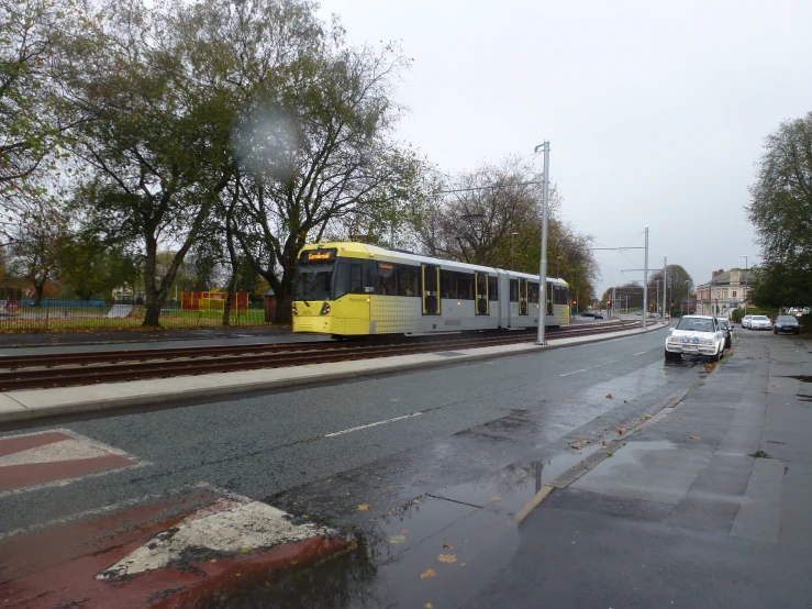 the yellow bus is travelling on the road through the rain