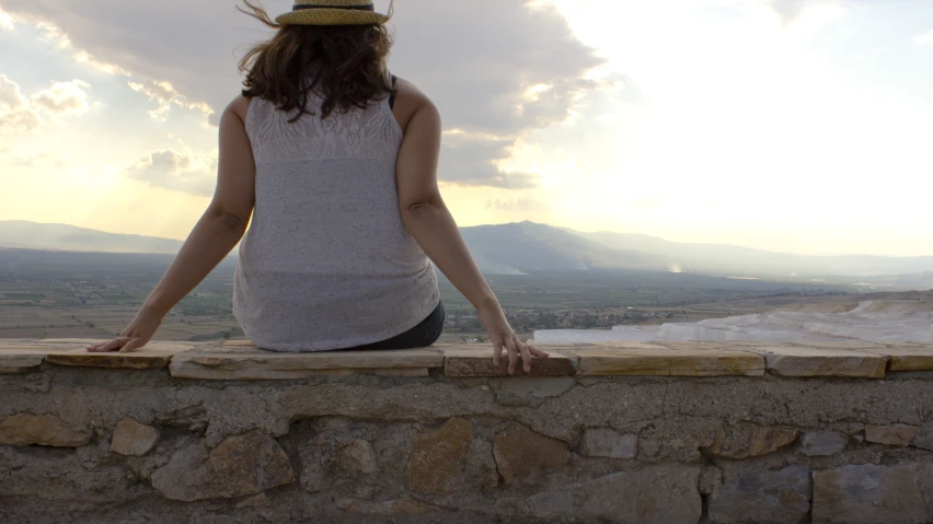 there is a woman sitting on the edge of a building with her arms outstretched