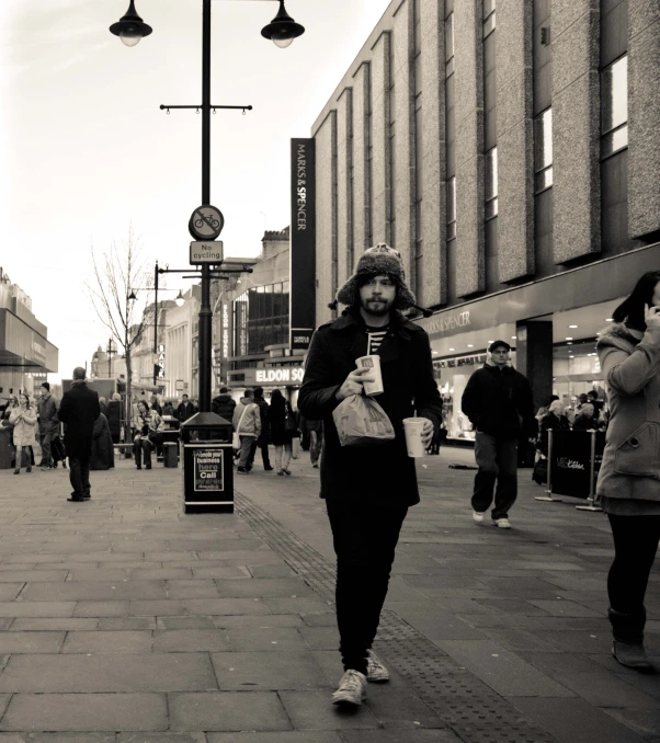 a woman walking down a sidewalk carrying shopping bags