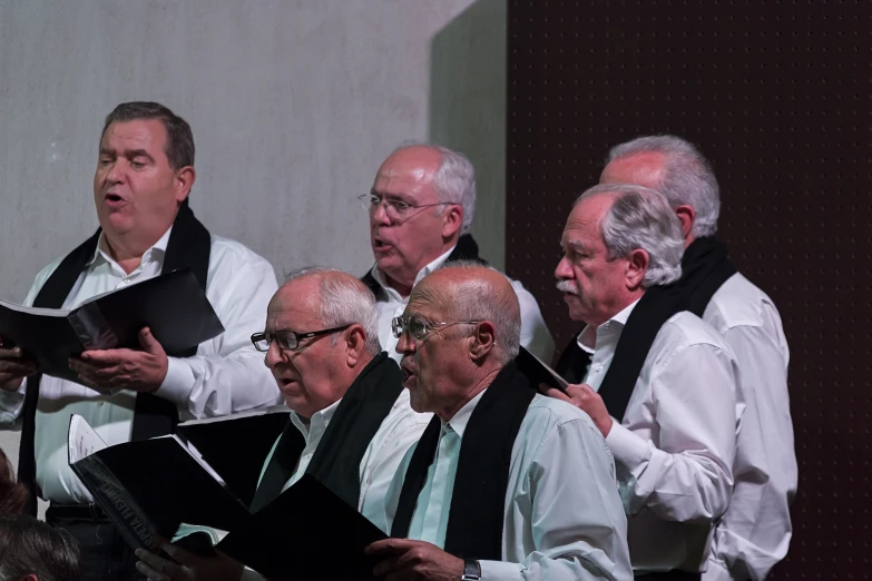 some people are standing with choirs holding sheet music