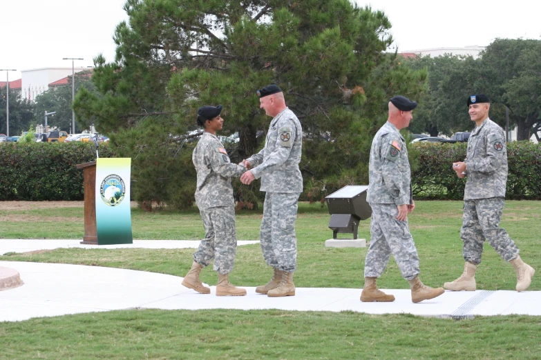 five military men dressed in uniforms shake hands at the base